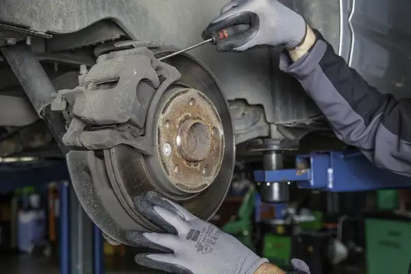 Mechanik w rękawiczkach sprawdza hamulce, by uniknąć bicia przy hamowaniu z dużej prędkości.