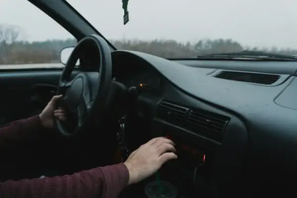 Ręka kierowcy manipuluje radiem samochodowym, szukając wskazówek, jak wyciągnąć radio samochodowe.