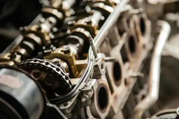 Zbliżenie na mechanizm rozrządu silnika, widoczny łańcuch i koła zębate. Może to być związane z problemem przedmuchów w silniku.