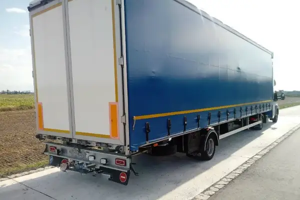 Ciężarówka z niebieską plandeką i białymi drzwiami z tyłu. Zastanawiasz się, ile waży ciągnik siodłowy?