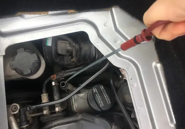 Sprawdzanie poziomu oleju silnikowego: check engine oil level co to znaczy. Dłoń wyciąga miarkę z silnika.