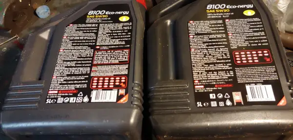 Dwie czarne butelki oleju silnikowego Motul 8100 Eco-nergy SAE 5W30 z etykietami.