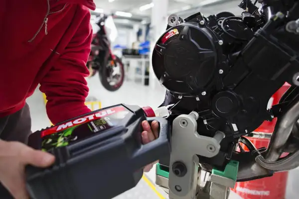 Wymiana oleju w motocyklu 125? Sprawdź, co ile zaleca producent. Mechanik nalewa olej Motul do silnika.