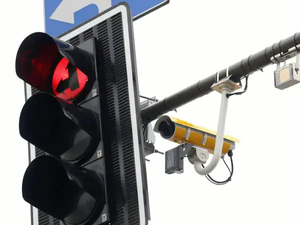 Czerwone światło sygnalizacji świetlnej ze strzałką w lewo i kamerą rejestrującą.